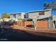 Exterior view of blue townhome complex, featuring a brick wall and clear blue skies at 510 N Alma School Rd # 103, Mesa, AZ 85201