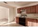 Efficient kitchen featuring wooden cabinets, classic white appliances, and light countertops with an open view to another room at 6132 E Casper St, Mesa, AZ 85205