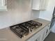 Close-up of a stainless steel gas cooktop with gray countertops and white backsplash at 7654 W Tether Trl, Peoria, AZ 85383