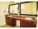 Bathroom vanity area featuring dual sinks, stylish mirrors and wood cabinetry at 9405 S 47Th Ave, Laveen, AZ 85339