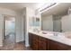 Bathroom featuring double sinks with dark wood cabinetry and a large mirror with views to the shower at 9556 W Frank Ave, Peoria, AZ 85382