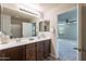 Bathroom featuring double sinks with dark wood cabinetry and a large mirror with views to the bedroom at 9556 W Frank Ave, Peoria, AZ 85382