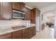 Beautiful kitchen featuring wood cabinets, stainless steel microwave, stone countertops, and light tile flooring at 9556 W Frank Ave, Peoria, AZ 85382