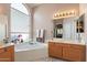 Bright bathroom featuring a soaking tub, double vanity, and a large window at 1310 S Vine Ct, Gilbert, AZ 85233
