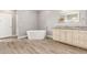 Bathroom with a large soaking tub, wood-look floors, and a vanity with stone countertop and a lighted mirror at 1600 W Ivar Rd, San Tan Valley, AZ 85144