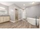 Bright bathroom featuring a soaking tub, walk-in shower, granite counters, and wood-look flooring at 1600 W Ivar Rd, San Tan Valley, AZ 85144