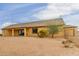 Back of home showing covered patio, desert landscaping, and slider to the interior at 1600 W Ivar Rd, San Tan Valley, AZ 85144