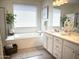 Bright bathroom featuring a large soaking tub, double vanity with white cabinetry, and stylish fixtures at 22443 E Munoz St, Queen Creek, AZ 85142