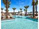 Resort-style pool featuring inviting blue water, palm trees, and comfortable lounging areas under a clear blue sky at 23090 E Lords Way, Queen Creek, AZ 85142