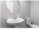 Clean, simple bathroom featuring a pedestal sink, a round mirror, and a toilet, perfect for a powder room at 24578 W Concorda Dr, Buckeye, AZ 85326