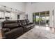 Stylish living room featuring a cozy leather sofa, large sliding glass doors and modern decor at 24578 W Concorda Dr, Buckeye, AZ 85326