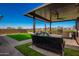 Inviting covered outdoor kitchen with seating, a built-in grill, and manicured green space at 24578 W Concorda Dr, Buckeye, AZ 85326
