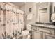Neutral bathroom with a shower featuring a patterned curtain, light gray vanity with granite counter, and a large mirror at 25925 W Mcrae Dr, Buckeye, AZ 85396