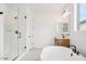 Bright bathroom featuring a soaking tub, glass-enclosed shower, and large window at 26361 N 76Th Dr, Peoria, AZ 85383
