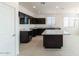 Modern kitchen features dark cabinetry, granite counters, and tile flooring at 36805 W San Clemente St, Maricopa, AZ 85138