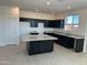 Modern kitchen with a center island, granite countertops, dark cabinets, recessed lighting, and stainless steel appliances at 36805 W San Clemente St, Maricopa, AZ 85138