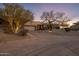Front exterior of the home with desert landscaping, mature trees, and a spacious driveway at 38951 N 101St Way, Scottsdale, AZ 85262