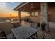 Covered patio with an outdoor kitchen, dining area, and serene desert views at sunset at 38951 N 101St Way, Scottsdale, AZ 85262