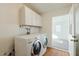 Bright laundry room featuring modern appliances, storage cabinets, and doorway at 4226 E Diamond Ave, Mesa, AZ 85206