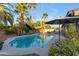 Backyard pool area surrounded by lush landscaping, patio furniture and a decorative patio umbrella at 5916 E Hearn Rd, Scottsdale, AZ 85254