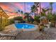 A backyard oasis with a sparkling pool, lounge chairs, and lush landscaping under a colorful sunset sky at 5916 E Hearn Rd, Scottsdale, AZ 85254