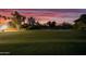 Night view of a meticulously groomed golf course, with the greens illuminated under a vibrant sunset at 7155 E Oakmont Dr, Paradise Valley, AZ 85253
