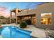 A luxurious backyard pool with a tile border, desert landscaping, a covered patio and a multi-story home at 11082 E Mark Ln, Scottsdale, AZ 85262