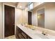 Well-lit bathroom featuring dual sinks, a large mirror, and a dark wood cabinet beneath at 11082 E Mark Ln, Scottsdale, AZ 85262