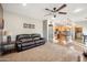 Comfortable living room with a ceiling fan, brown leather couch, and view into the open kitchen at 11451 E Starkey Ave, Mesa, AZ 85212