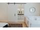 Bedroom view of sliding barn door leading to bathroom, clock and seating at 11745 N 99Th St, Scottsdale, AZ 85260