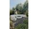 Outdoor entertaining area with a firepit and curved bench, accented by gravel and lush, mature landscaping at 11745 N 99Th St, Scottsdale, AZ 85260