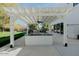 Outdoor kitchen boasts a modern pergola, counter space, and lush backyard view, ideal for gatherings at 11745 N 99Th St, Scottsdale, AZ 85260