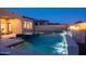Backyard swimming pool with outdoor fireplace and waterfall at dusk at 12245 E Clinton St, Scottsdale, AZ 85259