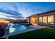 Backyard pool at dusk with an outdoor fireplace and waterfall at 12245 E Clinton St, Scottsdale, AZ 85259