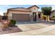 Attractive home featuring a two-car garage, stone accents, a well-manicured lawn, and a spacious driveway at 17063 W Nottingham Way, Surprise, AZ 85374