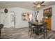 Dining area with wood-look floors, modern ceiling fan, adjacent to the living room and kitchen at 18080 W Udall Dr, Surprise, AZ 85374