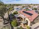 This aerial view showcases a desert home with solar panels, red tile roof, covered patio, and lush landscaping at 18400 N Deer Grass Ct, Surprise, AZ 85374