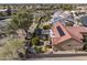 Bird's-eye view of a backyard oasis, with a covered patio, lush greenery, and a tiled roof under clear blue skies at 18400 N Deer Grass Ct, Surprise, AZ 85374