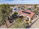 View of the desert home’s backyard with fire pit, covered patio, landscaping, and solar panels on a red-tiled roof at 18400 N Deer Grass Ct, Surprise, AZ 85374