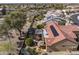 Bird's-eye view of a backyard oasis, with a covered patio, lush greenery, and a tiled roof under clear blue skies at 18400 N Deer Grass Ct, Surprise, AZ 85374