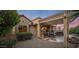Covered patio with outdoor dining set, grill, lush desert landscaping and palm trees at 18400 N Deer Grass Ct, Surprise, AZ 85374