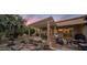 Relaxing outdoor space with a covered patio, water feature, and lush landscaping at twilight at 18400 N Deer Grass Ct, Surprise, AZ 85374