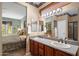 Bathroom with double sinks, and a view of the bedroom that includes a large window at 18400 N Deer Grass Ct, Surprise, AZ 85374
