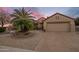 Inviting single-story home with desert landscaping, large palm tree, and two-car garage at 18400 N Deer Grass Ct, Surprise, AZ 85374
