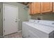 Bright laundry room with overhead cabinets, washer, dryer and tile flooring at 18400 N Deer Grass Ct, Surprise, AZ 85374