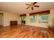 Spacious living room featuring hardwood floors, a ceiling fan, and natural light from large windows at 18400 N Deer Grass Ct, Surprise, AZ 85374