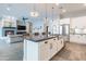 Open concept kitchen with stainless steel appliances, large island, fireplace and adjacent living room at 20618 W Western Dr, Buckeye, AZ 85396