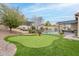 Putting green and sand trap surrounded by artificial turf in landscaped backyard with pool at 20618 W Western Dr, Buckeye, AZ 85396