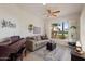 Comfortable living room featuring a plush sofa, piano, and a large window with a view of the golf course at 22416 N Arrellaga Dr, Sun City West, AZ 85375