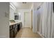 Bright bathroom with double sinks, dark wood cabinetry, and a glass-enclosed shower at 2325 S 88Th Dr, Tolleson, AZ 85353